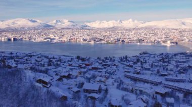 Norveç 'in Tromso şehrinin fiyort ve köprüsündeki karlı evlerin havası. Güneşli kış havası