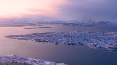 Norveç 'in Tromso kasabasının fiyort ve köprüsündeki karlı evlerin hava günbatımı manzarası. Güneşli kış havası