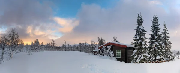 ノルウェーの山々の小さな雪に覆われた狩猟用ロッジ 前景の動物の痕跡と背景の山頂 — ストック写真