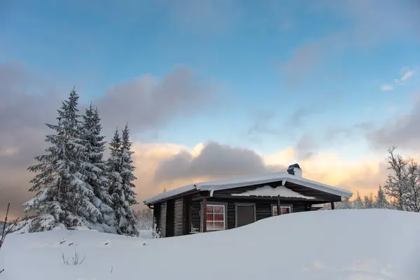 ノルウェーの山々の小さな雪に覆われた狩猟用ロッジ 前景の動物の痕跡と背景の山頂 — ストック写真