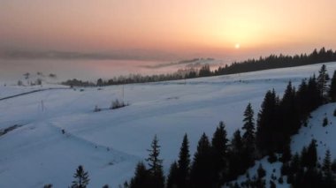 Karpatya dağlarının üzerindeki sis ve bulutlara insansız hava aracı görüntüsü. Güneşli kış, dondurucu soğuk.