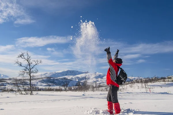 Sporty person in red sport jacket enjoys snow and breathtaking Norwegian landscape. Sunny winter activity.