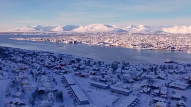 Kış mevsiminde Norveç 'in Trom kasabasının karla kaplı manzarasının üzerinde süzülüyordu. Resmedilmeye değer kıyı manzarası, buzlu fiyortlar ve şehir hayatı ile kutup çöllerinin eşsiz karışımı..
