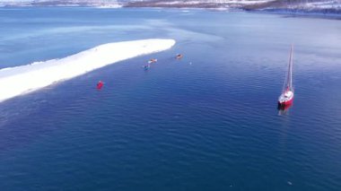 Norveç fiyortlarında kano ve yat. Norveç 'in kışın kıyı şeridinde kar, sıradağları kapladı. Troms İlçesi Fjordgard