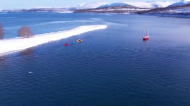 Norveç fiyortlarında kano ve yat. Norveç 'in kışın kıyı şeridinde kar, sıradağları kapladı. Troms İlçesi Fjordgard