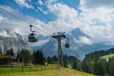 İsviçre Alplerinde kablolu bir araba. Jungfrau, Grindelwald 'dan Gondol. Karla kaplı arka planlı yaz Alp manzarası. Nakliye turistleri yokuş yukarı