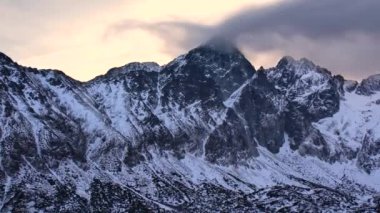 Alplerdeki karlı dağ manzarasının hava aracı görüntüleri. Dramatik bulutlu hava ve kayalık dağlar