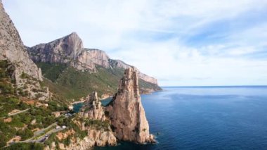 Sardegna 'daki Punrta Pedra Longa uçurumlarının insansız hava aracı görüntüsü. Sıcak turkuaz deniz, yükseklik kayaları ve Sardunya adasında yeşil dağları olan plaj..