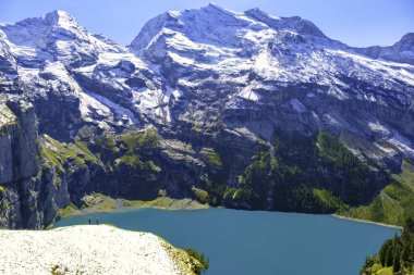 Güneşli yaz gününde Oeschinensee Gölü ve kar Bluemlisalp dağı. Gök mavisi Oeschinensee Gölü Panoraması, İsviçre Alpleri 'nde çam ormanı, Kandersteg. İsviçre.