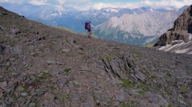 Sırt çantalı, yüksek bir dağ geçidi boyunca yürüyüş yapan sportif bayana hava manzarası. Grindelwald Vadisi İsviçre Alpleri güneşli günün tadını çıkarıyor.