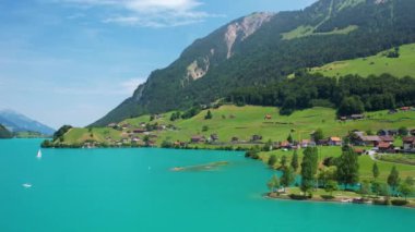 Güneşli yaz gününde İsviçre 'de Lungerersee ya da Lungerersee Gölü' nün turkuaz görüntüsü. Köy ve yeşil çayır.