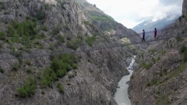 Oberaletsch ve Aletsch buzullarındaki asma köprüsü Belalp-Riederalp İsviçre 'deki iki turistin hava aracı görüntüsü.