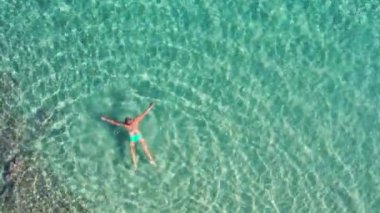 Sardunya Akdeniz 'in zümrüt yeşili sularında yüzen kadın. Yaz tatili ve rahatlama. Yukarıdan aşağıya insansız hava aracı atışı