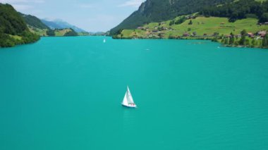 Güneşli yaz gününde İsviçre 'de Lungerersee ya da Lungerersee Gölü' nün turkuaz görüntüsü. Köy ve yeşil çayır.
