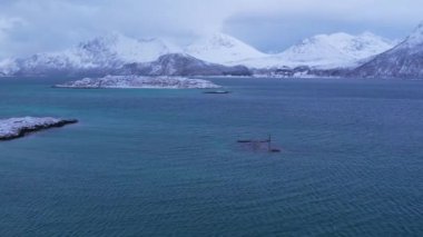 Norveç 'in Sommaroy adasında, güneşli kış mevsiminde, karla kaplı dağ zeminli bir kumsal çevresindeki hava manzarası