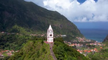Tarihsel saat kulesi Capelinha de Nossa Senyora de Fatima yemyeşil teras manzarası ve mavi okyanus Madeira adası Portekiz ile çevrili.