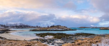 Sommaroy adalarının panoraması ve Tromso Norveç yakınlarında kutup denizi. Karlı küçük adaların üzerinde gün batımı