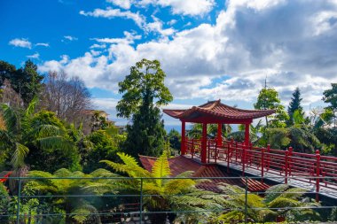 Portekiz 'in Madeira adasında popüler bir turizm merkezi olan Funchal şehrinin üzerinde kırmızı pagoda gölleri ve geleneksel binaları olan Monte Palace tropikal bahçesi.