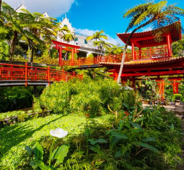 Portekiz 'in Madeira adasında popüler bir turizm merkezi olan Funchal şehrinin üzerinde kırmızı pagoda gölleri ve geleneksel binaları olan Monte Palace tropikal bahçesi.