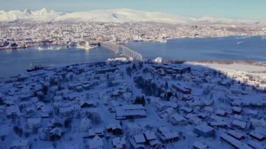 Kış mevsiminde Norveç 'in Tromso kasabasının karla kaplı manzarasının üzerinde süzülüyordu. Resmedilmeye değer kıyı manzarası, buzlu fiyortlar ve şehir hayatı ile kutup çöllerinin eşsiz karışımı..