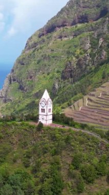 Tarihsel saat kulesi Capelinha de Nossa Senyora de Fatima yemyeşil teras manzarası ve mavi okyanus Madeira adası Portekiz ile çevrili.