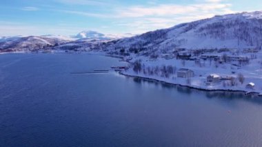 Norveç 'te kışın kışın kıyı şeridi karla kaplıydı. Kasabanın çevresi Tromso. İskandinav karından oluşan panoramik hava manzaralı dağlar, evler ve okyanus. Troms county, Fjordgard