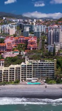 Praia Formosa sahilinin turkuaz sularının havadan görünüşü ve Funchal Madeira Adası Portekiz tepelerindeki renkli evler ve oteller