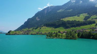Güneşli yaz gününde İsviçre 'de Lungerersee ya da Lungerersee Gölü' nün turkuaz görüntüsü. Köy ve yeşil çayır.