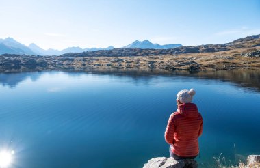 Sporty woman relaxing on the shore of a mountain lake Totensee in Switzerland on sunny day clipart