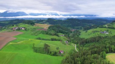 Yaz yağmurlu bir günde Avusturya kırsalının hava manzarası. Yeşil alanlar ve dağ manzarasının üzerindeki küçük köyler