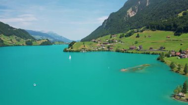 Güneşli yaz gününde İsviçre 'de Lungerersee ya da Lungerersee Gölü' nün turkuaz görüntüsü. Köy ve yeşil çayır.