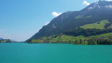 Güneşli yaz gününde İsviçre 'de Lungerersee ya da Lungerersee Gölü' nün turkuaz görüntüsü. Köy ve yeşil çayır.