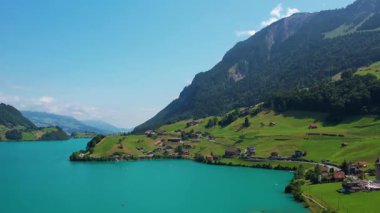 Güneşli yaz gününde İsviçre 'de Lungerersee ya da Lungerersee Gölü' nün turkuaz görüntüsü. Köy ve yeşil çayır.
