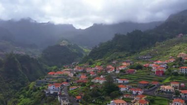 Sao Vicente, Madeira Adası, Portekiz 'in geleneksel teras köyünün havası. Fırtınalı havada yeşil bir dağ manzarası arasında küçük evler ve bahçeler.