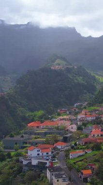 Sao Vicente, Madeira Adası, Portekiz 'in geleneksel teras köyünün havası. Fırtınalı havada yeşil bir dağ manzarası arasında küçük evler ve bahçeler.