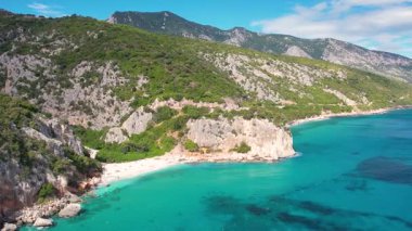 Sardegna Costa Smeralda 'daki Cala Fuili plajında hava aracı görüntüsü. Sardunya adasında yeşil dağlarla çevrili ılık turkuaz deniz ve küçük plaj.