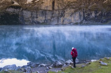 Sportif kız göldeki dağların yansımasına bakıyor. İsviçre Alplerinde Oeschinensee Gölü. Seyahat, macera, sağlıklı yaşam tarzı, seyahat tutkusu konsepti.