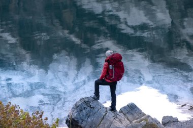 Sportif kız göldeki dağların yansımasına bakıyor. İsviçre Alplerinde Oeschinensee Gölü. Seyahat, macera, sağlıklı yaşam tarzı, seyahat tutkusu konsepti.
