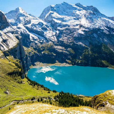 İsviçre Oeschinensee 'nin muhteşem manzarası. Turkuaz mavi alp gölü karlı dağların arasında. İsviçre Alplerinde yaz güneşli bir gün. Aktif spor ve yürüyüş için harika bir turistik cazibe