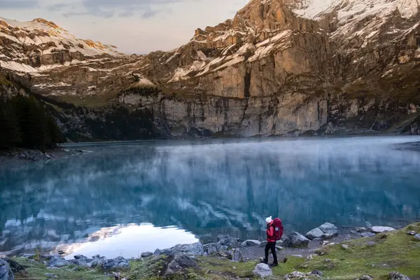 Sportif kız göldeki dağların yansımasına bakıyor. İsviçre Alplerinde Oeschinensee Gölü. Seyahat, macera, sağlıklı yaşam tarzı, seyahat tutkusu konsepti.