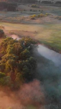 Güneşin sisli nehir üzerinde doğuşunu gösteren hava aracı görüntüsü. Sakinlik, rahatlama, meditasyon, yalnızlık, doğa konseptinin güzelliği.
