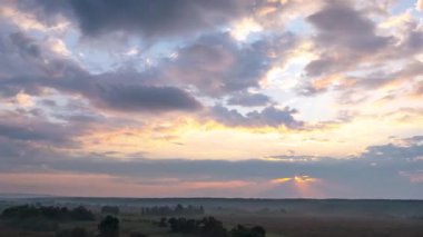 Kırsal arazinin üzerindeki dramatik günbatımı zamanı. Kırsal bölgede hareket eden pembe bulutlar.