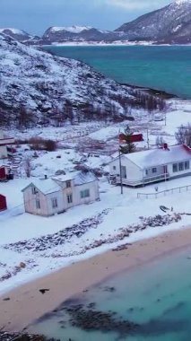 Norveç 'in Sommaroy adasında, güneşli kış mevsiminde, karla kaplı dağ zeminli bir kumsal çevresindeki hava manzarası