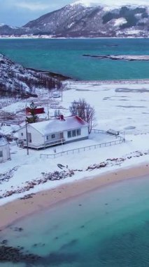Norveç 'in Sommaroy adasında, güneşli kış mevsiminde, karla kaplı dağ zeminli bir kumsal çevresindeki hava manzarası