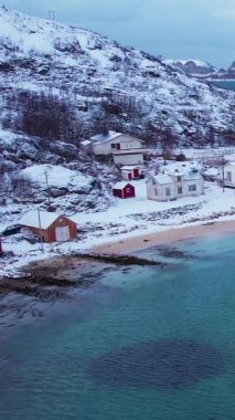 Norveç 'in Sommaroy adasında, güneşli kış mevsiminde, karla kaplı dağ zeminli bir kumsal çevresindeki hava manzarası