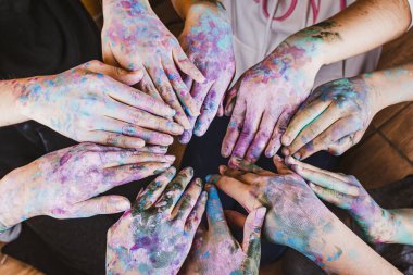 Elleri farklı renklerde boyanmış bir grup insan.