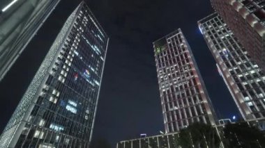 Gece gökyüzünün önündeki iş binalarının teknoloji efektli alt görüntüsü