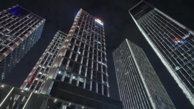 Gece gökyüzünün önündeki iş binalarının teknoloji efektli alt görüntüsü