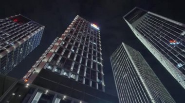 Gece gökyüzünün önündeki iş binalarının teknoloji efektli alt görüntüsü