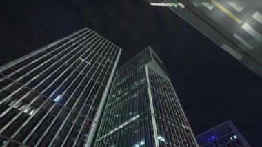 Gece gökyüzünün önündeki iş binalarının teknoloji efektli alt görüntüsü